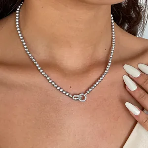 Detailweergave van een zilveren kralenketting met een fonkelende geometrische sluiting