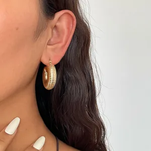 Detailansicht goldene, strukturierte Creolen mit geripptem, minimalistischem Design