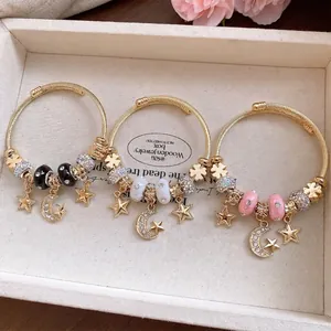 Set of three gold-tone twisted wire bangles with rhinestone star and moon charms