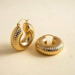 Detailansicht goldfarbener, gerippter Creolen mit strukturiertem geometrischem Design.