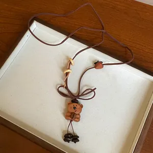 Detailed view of a cute wooden bear pendant necklace with a brown velvet cord.
