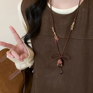 Detail showing a wooden bear pendant on a brown velvet necklace cord with a bow knot