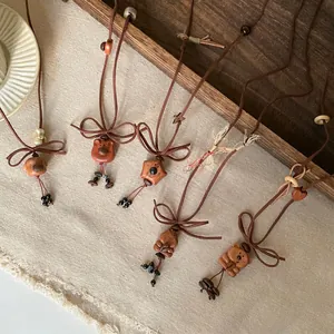 Close-up of wooden and resin bear and puppy pendant necklaces on brown velvet cords.