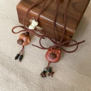 Close-up of cute wooden puppy and bear pendants on soft brown velvet necklace cords