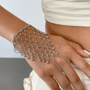 Detailansicht eines silbernen Handketten-Armbands mit Spinnennetz-Muster an einem Model.