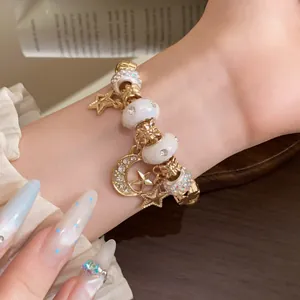 Detailansicht eines Armbands mit Stern- und Mondanhängern am Handgelenk einer Frau