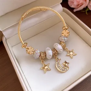 Detailaufnahme eines goldenen Stern- und Mond-Charm-Armbands mit Kristallen in einer Geschenkbox