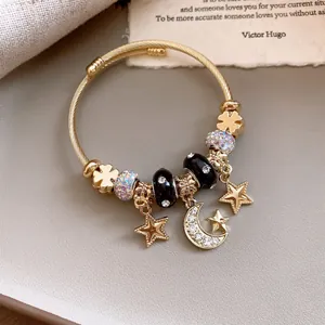 Detailansicht des goldenen Armbands mit Stern- und Mondanhängern und Strasssteinen.