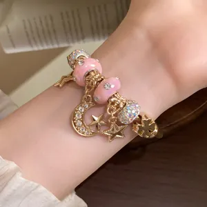 Detailansicht eines vergoldeten Bettelarmbands mit rosa Perlen und Stern-Mond-Anhängern
