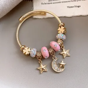 Detailansicht eines goldenen Armreifs mit rosa Perlen und Kristall-Mondanhängern