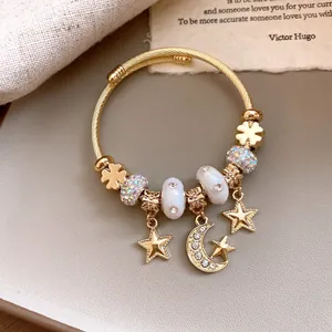 Detailansicht eines goldenen Armbandes mit Stern-Mond-Anhängern und Kristallen.