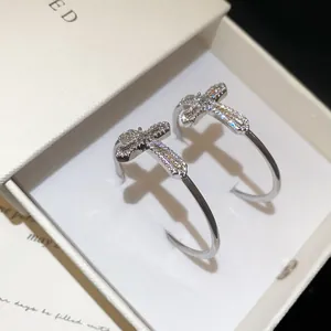Détail en gros plan de boucles d'oreilles croix en argent avec oxydes de zirconium