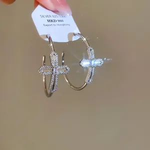 Vue détaillée de créoles croix avec zircons scintillants et étiquette en argent 925