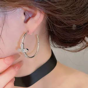 Gros plan détaillé d'une boucle d'oreille créole en croix avec zircons brillants