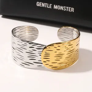 Close-up van tweekleurige roestvrijstalen manchetarmband met gehamerde textuur in goud en zilver.