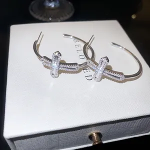 Gros plan détaillé d'un pendentif croix en zircon brillant sur des boucles d'oreilles