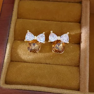 Detail van 14k vergulde vierkante bruine zirkonia oorbellen met een strikdetail