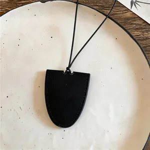Gedetailleerde weergave van een zwarte lederen ovale hangerketting op een keramisch bord.