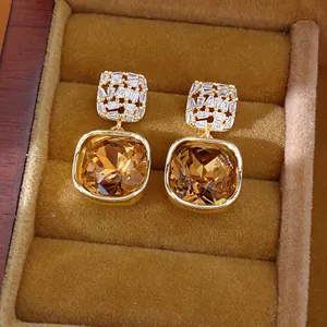 Detail van luxe 14k vergulde vierkante oorknopjes met champagnekleurige zirkoon