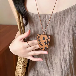 Detailweergave van een leren brillenhouder hanger met luipaardprint aan een ketting