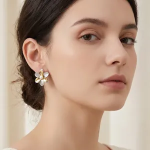 Detaillierte Nahaufnahme eines eleganten zweifarbigen Blumenohrrings mit Perle am Model