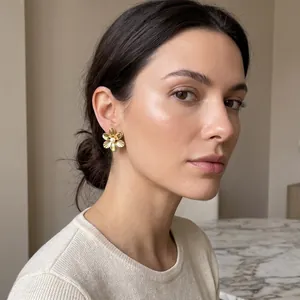 Nahaufnahme eines eleganten, 18 Karat vergoldeten Blumenohrrings mit Perle am Model