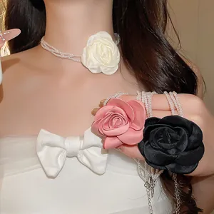 Nahaufnahme eleganter Perlen-Choker mit farbigen Stoffrosen in Weiß, Rosa