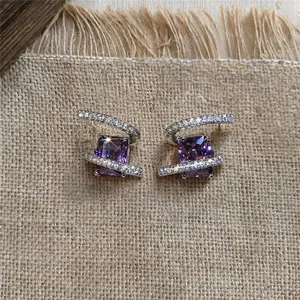 Détail de boucles d'oreilles carrées en zircon violet avec bandes scintillantes.