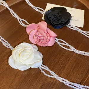 Makrodetail von Vintage Rosen-Perlenhalsketten in weißem, pinkem und schwarzem Satin.