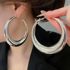 Close-up van grote zilveren metalen oorringen met een gladde en glanzende spiegelafwerking