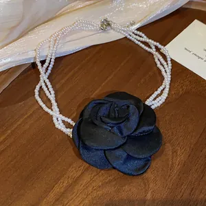Detail eines Vintage-Perlen-Chokers mit einer großen schwarzen Satin-Rose verziert.