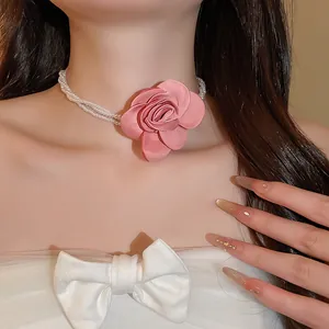 Nahaufnahme eines Vintage-Perlen-Chokers mit einer großen rosa Stoffrose am Hals.