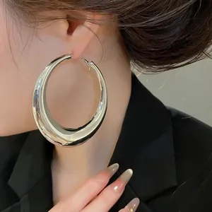 Close-up van overdreven grote dikke zilveren oorringen op een Aziatisch model, sieraden
