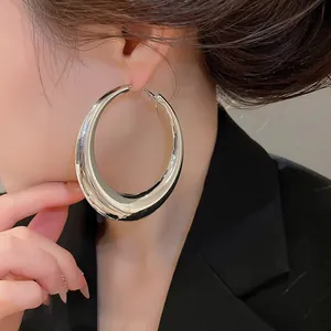 Close-up van grote gepolijste zilveren oorringen op een Aziatisch model voor een chique look