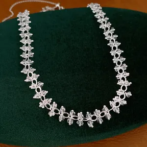 Detailopname van geometrische zirkoon kralenketting op groene fluwelen display.