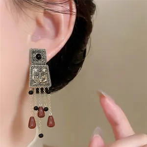 Nahaufnahme von Vintage-Quastenohrringen im Palaststil mit geometrischen Formen und Perlen.