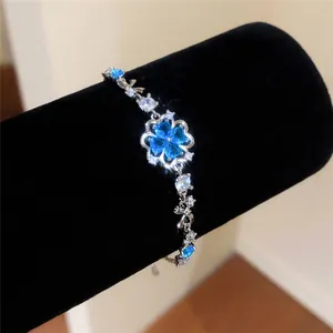 Macro view of a sparkling silver bracelet with a blue zircon flower on a black display