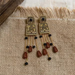 Makrodetail der Vintage-Palast-Ohrringe mit goldenen Quasten und braunen Perlen