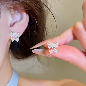 Detailed view of dainty zircon bow knot stud earrings featuring a pearl and heart-shaped drops.