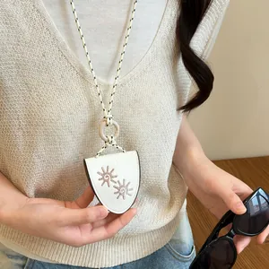 Close-up detail of white leather necklace with sun embroidery used as an eyeglass holder