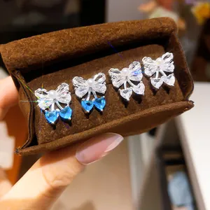 Detailed view of elegant zircon bow earrings with heart pendants in a jewelry box