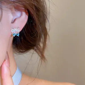 Detailed view of elegant zircon bow earrings featuring blue heart cherry pendants