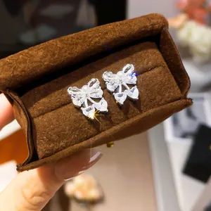 Close-up of elegant silver bow-knot stud earrings with sparkling zircons and pearls
