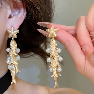 Close-up detail of vintage ocean style starfish and fish drop earrings with pearls
