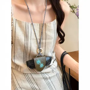 Detailed view of a model wearing a green leather glasses holder necklace with sun embroidery