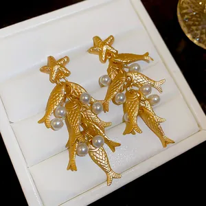 Close-up detail of vintage matte gold fish and starfish earrings with white pearls