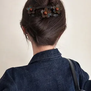 Achteraanzicht van een vrouw met een grote acryl bloem haarclip in een opgestoken kapsel.