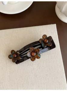Gedetailleerd vooraanzicht van een acryl haarclip met stijlvolle bloemen in schildpadpatroon