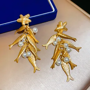Detailed macro shot of vintage ocean-style gold fish and starfish earrings with pearls.