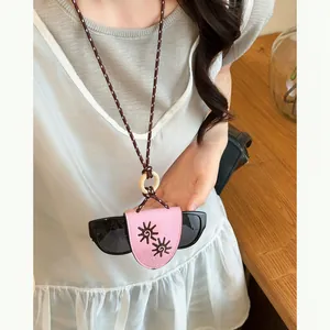 Detailed view of a pink leather sunglass holder necklace with sun embroidery on a model.